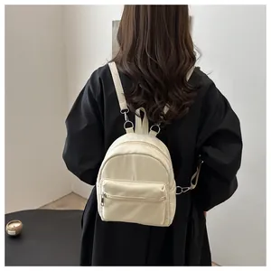 Vista detallada de una mini mochila blanco roto en modelo con ganchos de metal
