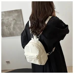 Mochila pequeña de nailon blanco roto con correas ajustables llevada por una modelo