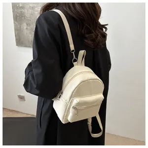 Vista detallada de una mini mochila de nailon crema con correas ajustables y cremalleras