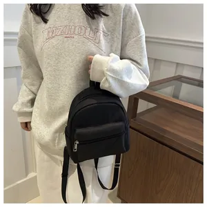 Vista lateral de una pequeña mochila negra de nailon impermeable con varios bolsillos