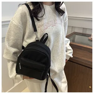 Primer plano de una mini mochila negra ligera con cremalleras plateadas en modelo