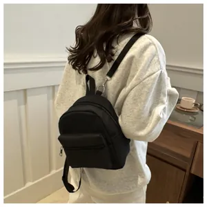 Vista posterior de una mini mochila negra minimalista en una modelo en estilo casual