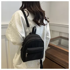 Detalle de la mochila pequeña negra de nailon impermeable con cremalleras metálicas plateadas