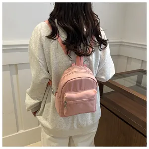 Detalle de una mini mochila de nailon rosa claro con bolsillos usada por una modelo