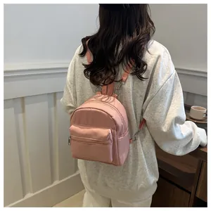 Vista trasera de una mochila rosa de nailon impermeable con correas ajustables en un modelo
