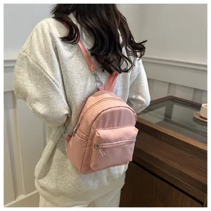 Mini mochila rosa impermeable con correas ajustables mostrada en vista trasera sobre modelo