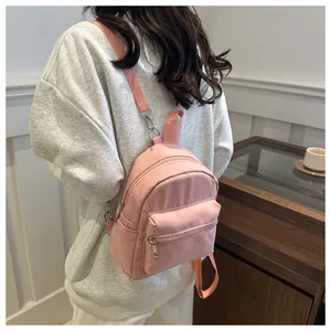 Mini mochila de nailon rosa con vista lateral trasera usada en un ambiente acogedor