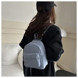 Mini mochila impermeable gris azulado en la espalda de una modelo para ver el tamaño