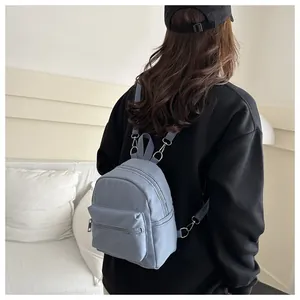 Vista posterior de una modelo con una mini mochila azul claro y diseño multibolsillos