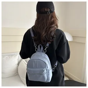 Detalle de mini mochila azul claro con cremalleras dobles y correas ajustables en modelo