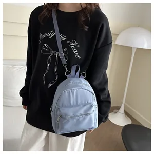 Detalle de una mini mochila azul claro con correas ajustables y diseño multibolsillo