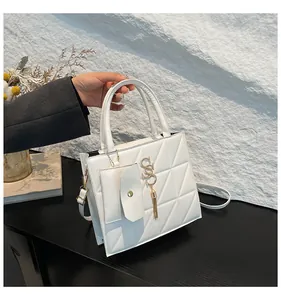 Close-up of a white quilted handbag with decorative S-pendant and small pouch detail