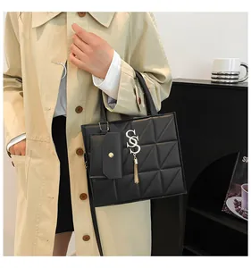 Close-up of elegant black quilted handbag with gold hardware held by a model in a beige coat