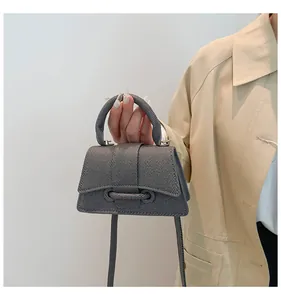 Close-up of a grey hourglass-shaped mini handbag with textured surface and thin strap