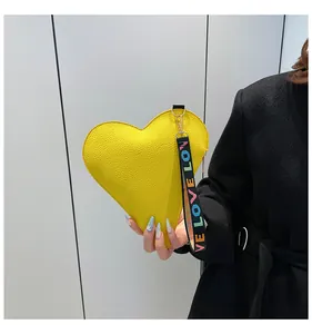 Vue détaillée d'un sac à main jaune en forme de cœur avec dragonne colorée « LOVE ».