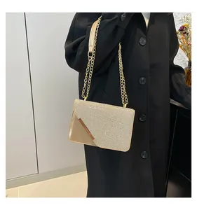 Detailaufnahme der goldenen Glitzer-Umhängetasche mit Kette auf schwarzem Mantel