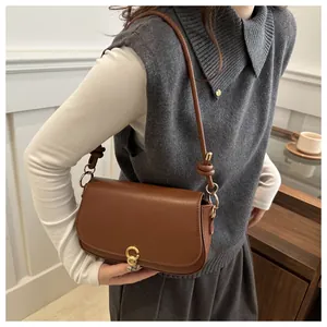 Detail einer braunen Satteltasche aus Leder mit goldener Schnalle und geknotetem Riemen