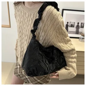 Detail of glossy black water-ripple shoulder bag featuring unique scrunchie strap design