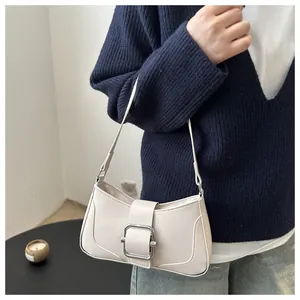 Detailed view of cream leather crescent bag with a large silver buckle on a model