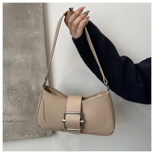 Detail of elegant beige faux leather shoulder bag featuring a silver metal square buckle