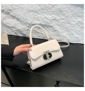 Close-up of beige handbag with gold T-shaped swivel lock and premium leather texture