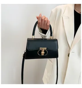 Close-up of black matte leather handbag with gold metal lock and elegant top handle