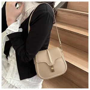 Detail of light beige saddle bag with gold metal clasp and smooth leather texture shown on model