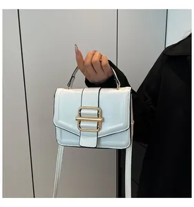 Detail of white leather handbag featuring elegant gold metal clasp and textured flap cover