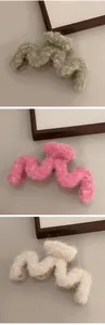 Detail of plush wavy hair claws in green, pink, and cream with soft faux fur texture