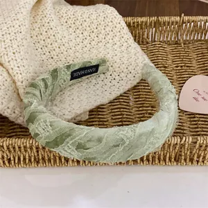 Serre-tête rembourré en dentelle vert sauge avec étiquette faite main dans un panier
