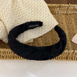 Détail du serre-tête noir texturé fait main avec dentelle et étiquette de fabrication