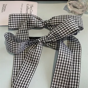 Detail of elegant black and white plaid bow hair clips with long fabric ribbons
