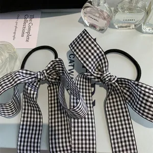 Detail of two black and white plaid bow hair ties styled with elegant long ribbon tails