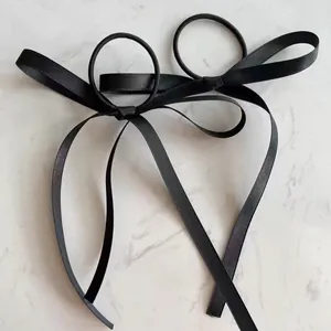 Elegant black satin bow hair ties with long ribbons on marble background, 2-pack set