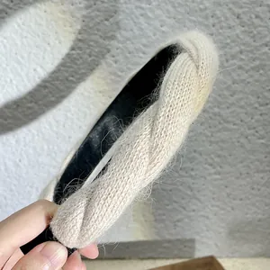 Gros plan d'un bandeau en tricot beige avec texture pelucheuse et nœud torsadé chic
