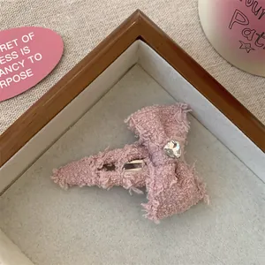 Detail van roze tweed strik haarclip met hartvormige strass op houten display