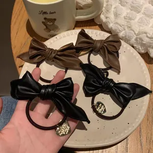 Elegant leather bow hair ties in black and brown colors with golden heart charm