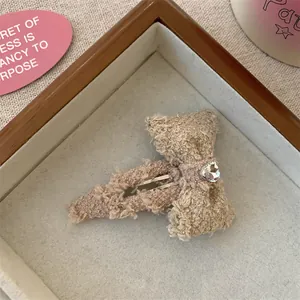 Detail van lamswollen strik haarclip met hartvormige strass op een houten dienblad