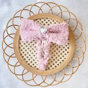 Stijlvolle pluche roze strik haarclip met hartvormige strass op een geweven dienblad