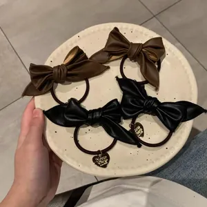 Bow hair tie set in black and brown faux leather with heart-shaped metal charms