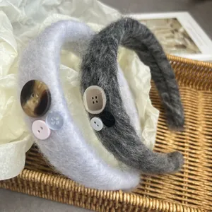 Detail of plush mohair headband with decorative vintage buttons on textured straw mat