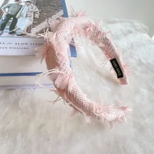 Detailed view of pink tweed headband with hand made label and frayed edge texture