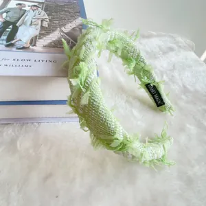Detail of green and white tweed headband with soft feathers and handmade label
