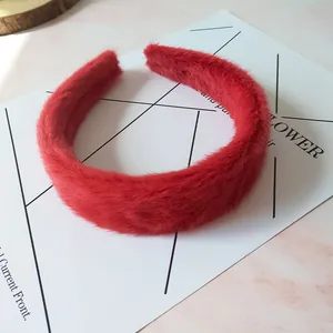 Primer plano de una diadema esponjosa de piel sintética roja sobre fondo de mármol rosa