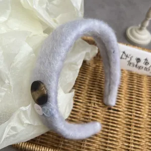 Detail of light blue fuzzy headband with retro buttons and soft mohair texture