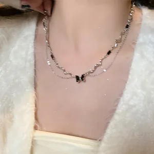 Detail view of double-layered silver necklace with black butterfly pendant on neck