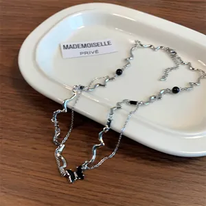 Double-layered silver necklace featuring a black butterfly pendant and irregular wave chain