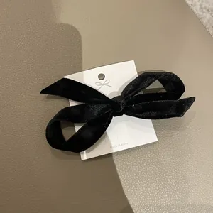 Elegant black velvet bow hair clip on premium leather background, minimalist hair accessory