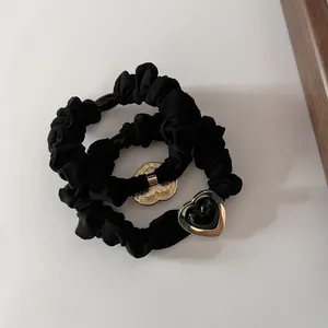 Set de dos coleteros de satén negro con colgantes de corazón dorados sobre fondo blanco
