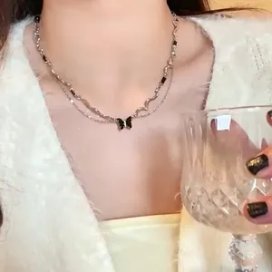 Silver layered butterfly necklace with black enamel accents on a model in white clothing